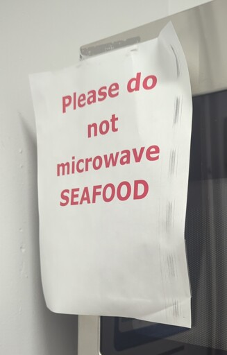 Photo of a paper taped to a microwave that says please do not microwave seafood